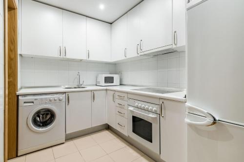 a kitchen with white cabinets and a washer and dryer at Plaza Mayor II - Apartamento de 2 dormitorios in Madrid