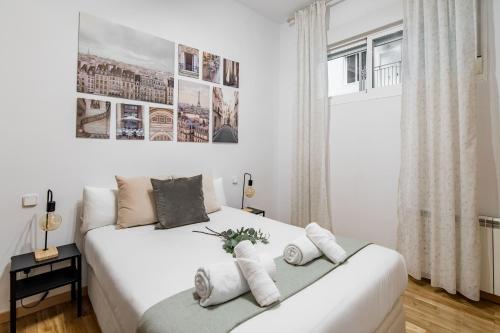 a white bedroom with two beds and a window at Plaza Mayor II - Apartamento de 2 dormitorios in Madrid