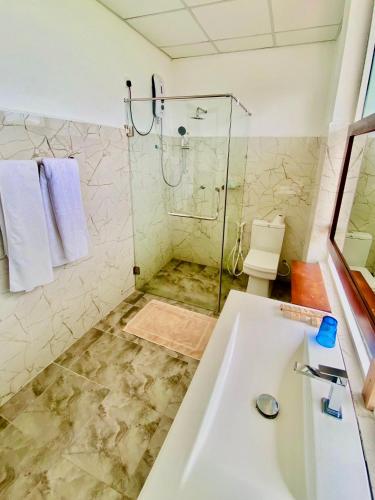 a bathroom with a shower and a sink at Organic Garden Resort Sigiriya in Sigiriya