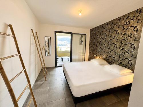 une chambre avec un lit et un mur en pierre dans l'établissement T2 moderne avec vue mer et proche centre-ville, à Propriano