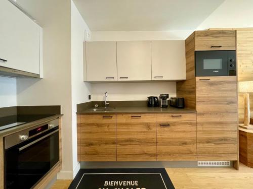 une cuisine avec des armoires en bois et un évier dans l'établissement Homency - Résidence Fermes de l'Alpe A001, à L'Alpe-d'Huez