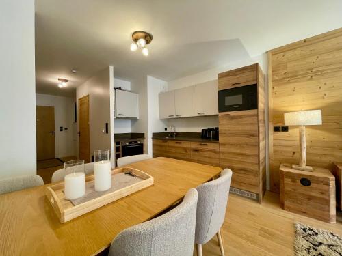 une cuisine et une salle à manger avec une table et des chaises en bois dans l'établissement Homency - Résidence Fermes de l'Alpe A001, à L'Alpe-d'Huez