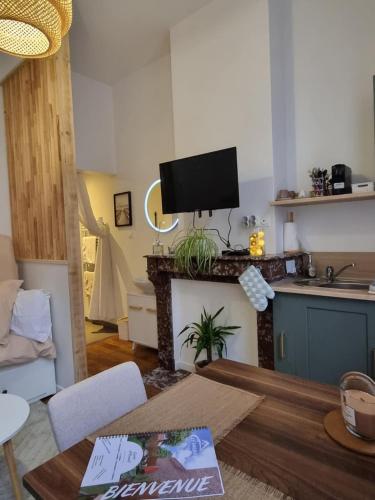 a living room with a table and a tv on a fireplace at Le Vauban Cambrai in Cambrai