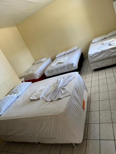 three beds are lined up in a room at Hotel Asa Branca in Boa Vista