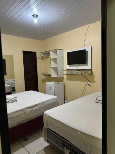 a room with two beds and a tv on the wall at Hotel Asa Branca in Boa Vista