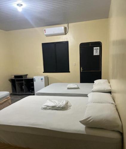 a bedroom with two beds and a air conditioner at Hotel Asa Branca in Boa Vista