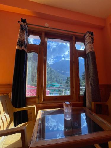 a table and a window with a view of a mountain at Trippy Homestay in Kasol
