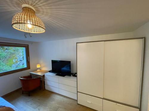 Habitación con escritorio, TV y lámpara de araña. en Studio Montaña, en Planay