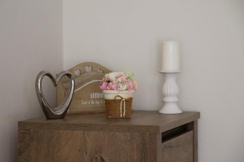 a basket of flowers on a table with a heart shaped mirror at Anna Apartman in Százhalombatta
