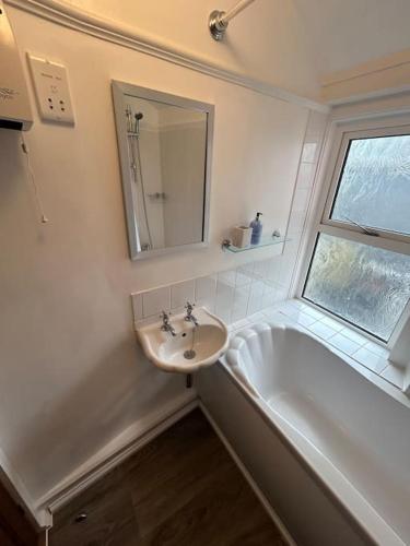 a bathroom with a sink and a tub and a mirror at The Pink House in Torquay