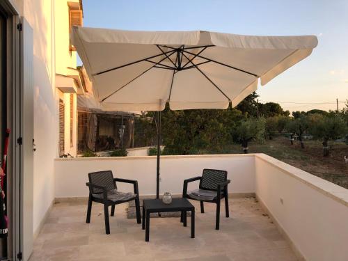 two chairs and a table with an umbrella on a balcony at Dimora Caraspi in Mola di Bari