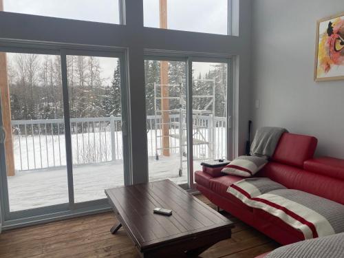 a living room with a red couch and a coffee table at Le Monk ,chalet, motoneige, quad ,nature, randonné pédestre in Montmagny