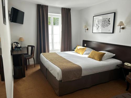 a hotel room with a bed and a desk at Logis Hotel Le Richelieu - Royan Atlantique in Saujon