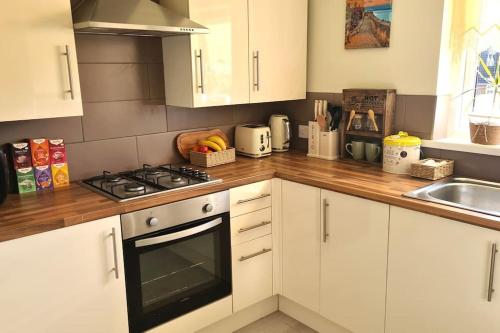 a kitchen with white cabinets and a stove top oven at The Art Gallery Guest House - Newport Cozy 3-Bedroom Home in Newport