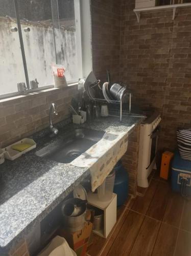 a kitchen counter with a sink and a window at Pousada Recanto das Margaridas in Boicucanga
