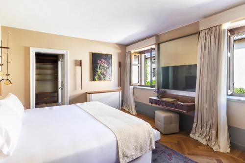 a bedroom with a large bed and a television at Borgo Dei Conti Resort Relais & Chateaux in Monte Petriolo