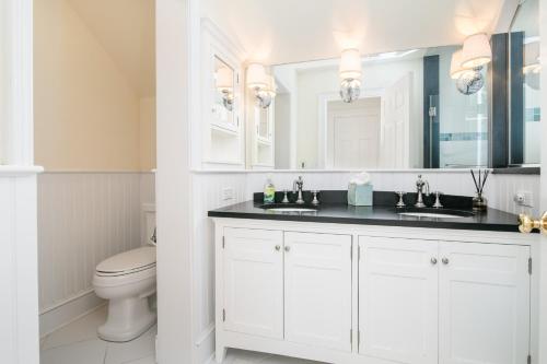 a white bathroom with a toilet and a sink at Baydream Believer in Saint Michaels
