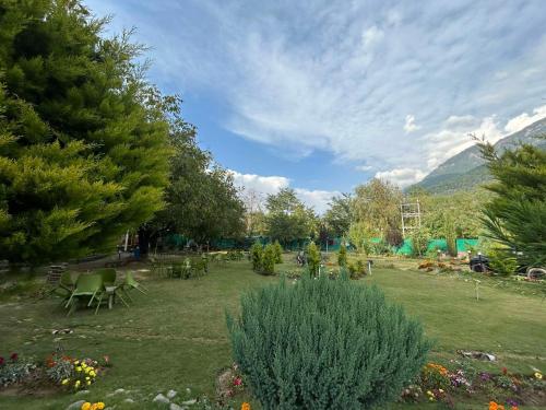 a garden with chairs and tables and trees at Lidder view Resorts in Pahalgām