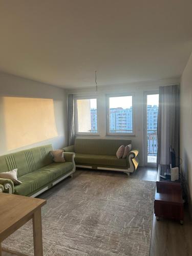 a living room with a green couch and windows at Fushe kosove pristina daire otel apart in Kosovo Polje