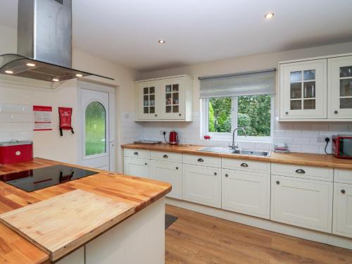 a kitchen with white cabinets and a wooden counter top at Inglenook in Ulverston