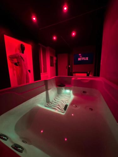 - une baignoire blanche dans une chambre avec des lumières rouges dans l'établissement La squid love jacuzzi & cinema prive, à Melun