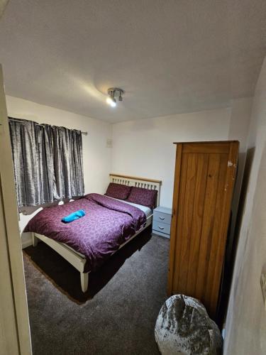 1 dormitorio con 1 cama con edredón morado en London Serviced Accommodation x RM10 x DM 4 Weekly x Monthly Deals x Sleeps 10 x FREE Parking x FREE Wifi E, en Dagenham