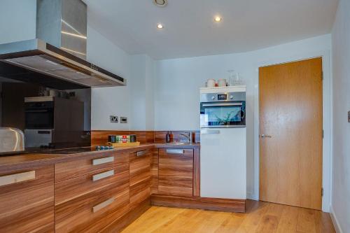 a kitchen with wooden cabinets and a white refrigerator at Blonk Street I Quarter Apartment in Sheffield