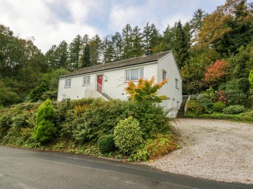 a white house with a red door on a road at Inglenook in Ulverston