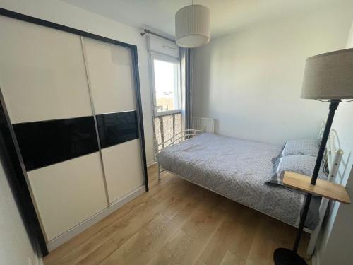une chambre avec un lit et une grande fenêtre dans l'établissement Appartement T3 proche Paris Stade de France, à Saint-Denis