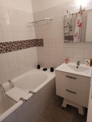 une salle de bain blanche avec une baignoire et un lavabo dans l'établissement Grand appartement proche métro quartier la defense, à Courbevoie