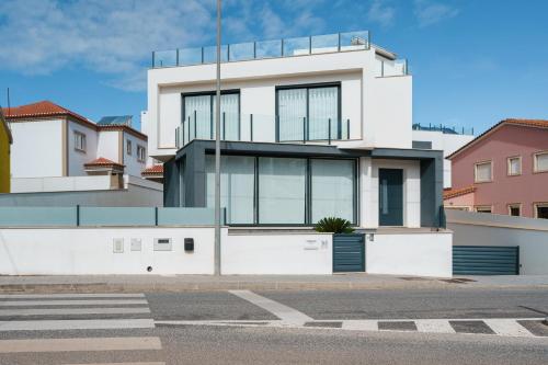 a white building with glass windows on a street at Ammos Villa, beach villa with ocean view in Ribamar