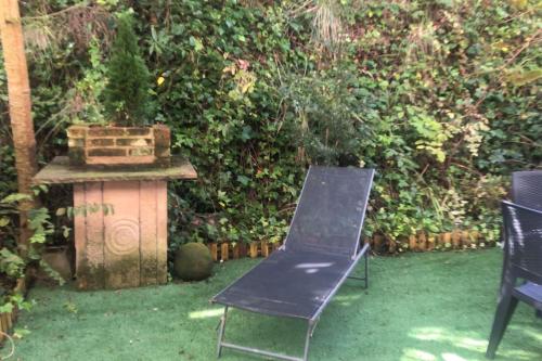 a black chair sitting in a yard next to a bush at Casa de Claudia Comillas- Jardín privado - A 10 metros del Capricho de Gaudí in Comillas