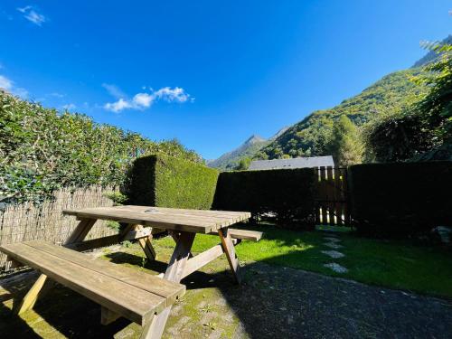 a wooden picnic table sitting in front of a fence at "La clé dorée" Chalet mitoyen avec jardin et -WIFI- in Cauterets