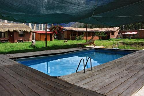 a swimming pool with a wooden deck and an umbrella at Pitusiwasi Guest House in Calca