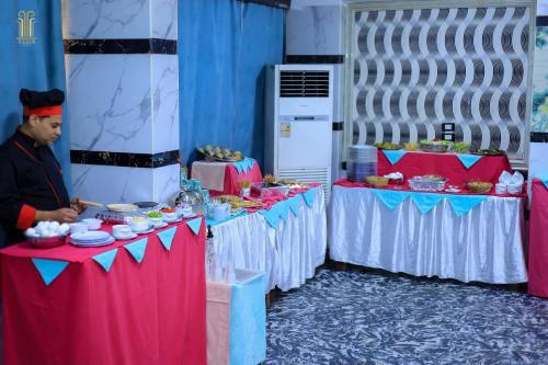 a man standing next to two tables with food on them at Tiba Hotel in Aswan