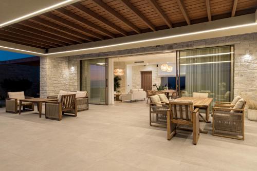 a patio with tables and chairs and a living room at POEMO VILLAS in Ierápetra