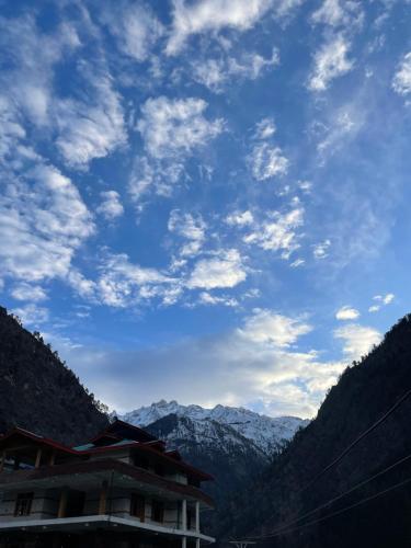 a blue sky with clouds above a mountain at Trippy Homestay in Kasol