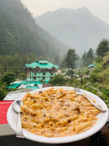 a plate of pasta on a table with a fork at Trippy Homestay in Kasol