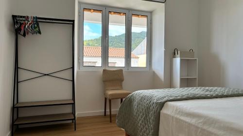 a bedroom with a bed and a chair and a window at Casa Cidalisa in Povoação