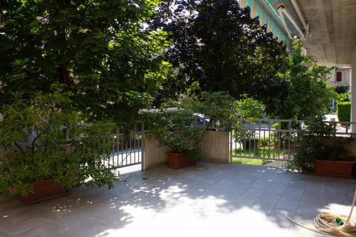 a fence with trees and plants in a courtyard at Appartamento moderno e tranquillo in Piacenza