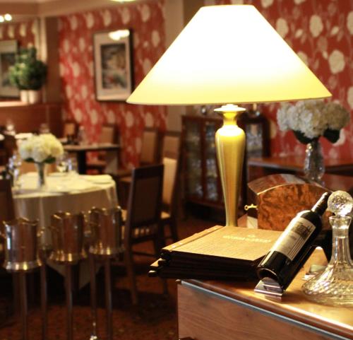 a lamp on a table with a book and a bottle of wine at Vaughan Lodge Hotel in Lahinch