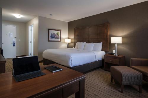 a hotel room with a bed and a desk with a laptop at Comfort Inn - Gander in Gander