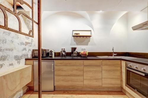 une cuisine avec des armoires en bois et un évier dans l'établissement Bluestay 221 - Appartement au centre de Paris, à Paris
