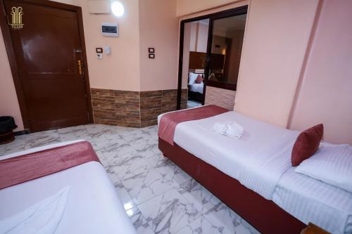 a hotel room with two beds and a mirror at Tiba Hotel in Aswan