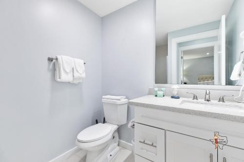 a white bathroom with a toilet and a sink at Bahia Mar Solare Beachfront Resort Condos with Two Pools in South Padre Island