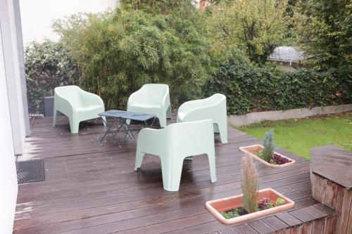 a deck with white chairs and a table and cactus at Un cocon à deux pas de Paris in Arcueil