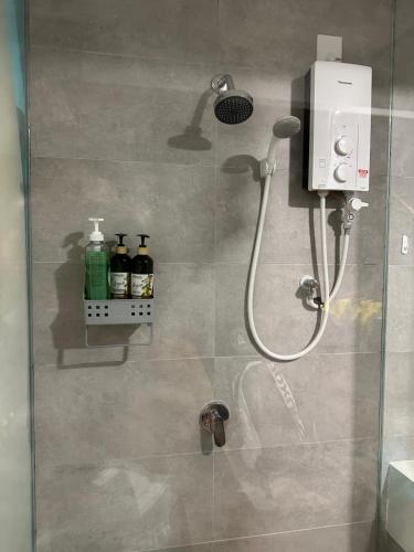 a shower with a glass door with bottles on the wall at Riveria City KL Sentral in Kuala Lumpur