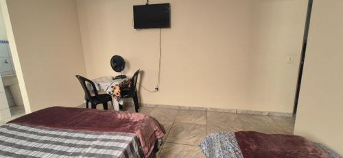 a bedroom with a bed and a table and a television at Kit GT in São Carlos