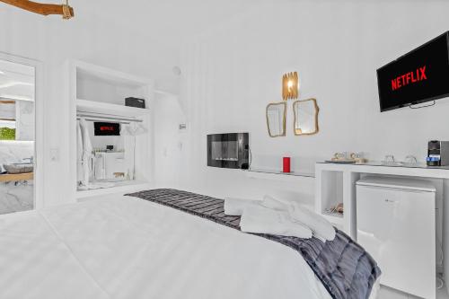 a white bedroom with a bed and a tv at Blue Mountain Guesthouse by Seablue in Arachova