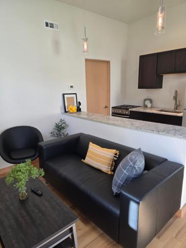 a living room with a black couch and a kitchen at Guesthouse in Tower Grove